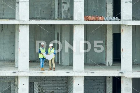 Construction engineers reading draft in unfinished building Stock Photos