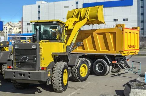 Construction Equipment front loader loading the truck (all logos, inscript... Stock Photos