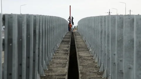 Construction equipment installs or adjusts a metal barrier along the road. Stock Footage 329869085