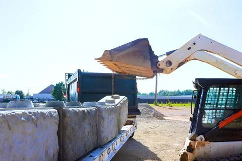 Construction equipment loads heavy materials onto truck at construction site in Stock Photos