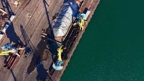 Construction equipment loads materials at a dock by the water during daytime Stock Footage 335381614
