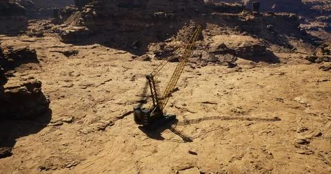 Construction equipment operates in rugged desert terrain during daylight hour Illustrazione stock