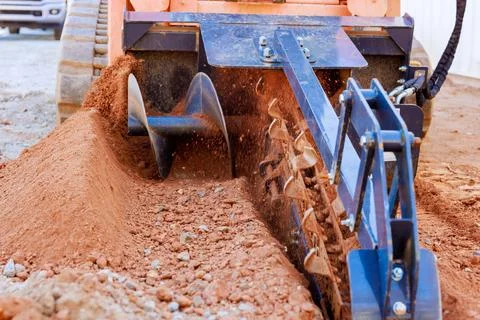 Construction equipment working on soil preparation in an outdoor site during Stock Photos