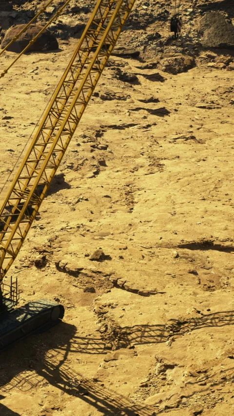 Construction equipment works on a dry riverbed in a rugged landscape Vidéo 331753996