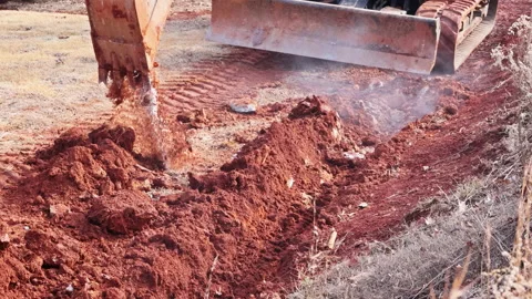 Construction equipment works on red soil to prepare land for building Stock Footage 337887245