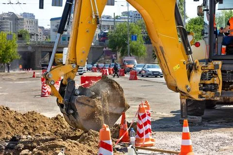 A construction excavator operator skillfully operates a bucket to dig a trenc Stock Photos