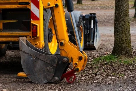 A construction excavator is preparing for landscaping work in the park Stock Photos