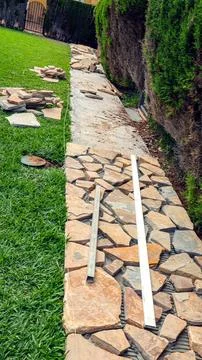 Construction of flagstone walkway next to green grass during garden landsca.. Stock Photos