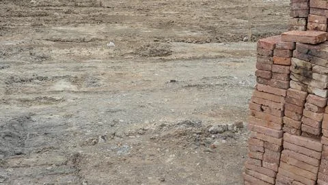 A construction foreground with a stack of red-orange bricks on the right. T.. Stock Photos