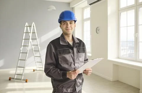 Construction foreman with blue hard hat and clipboard in bright renovated room Stock Photos