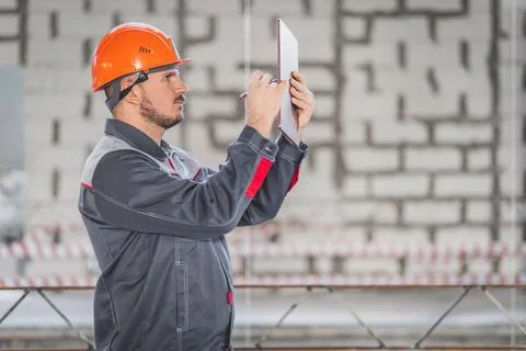 Construction foreman with digital tablet and stylus in hand making sketches for Stock Photos