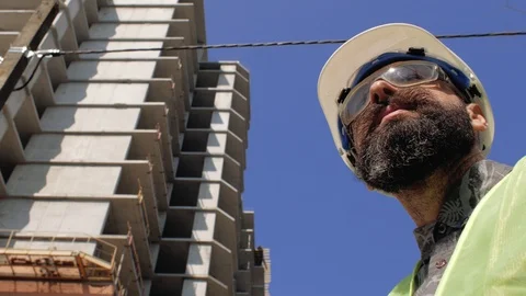 Construction foreman in a helmet near the construction site of a building. 4 k Stock Footage 106019945