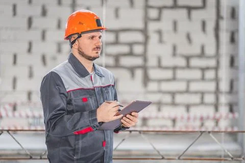 Construction foreman worker in helmet and uniform controlling building site with Stock Photos