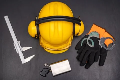 Construction helmet, handcuffs and vodka in a bottle. Drunkenness at work in  Stock Photos