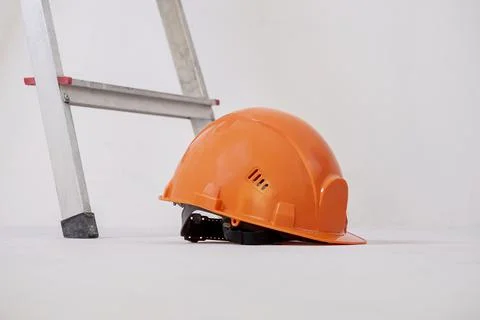 Construction helmet is lying against plaster wall. Stock Photos