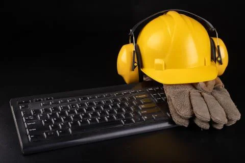 Construction helmet, work gloves on the computer keyboard. Work clothes for a Stock Photos