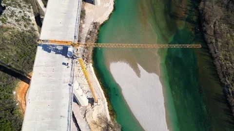 The construction of a high concrete bridge over the river Stock Footage 275853820