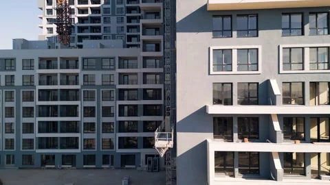 Construction hoist moving up between modern multi-story residential buildings Stock Footage 346233610