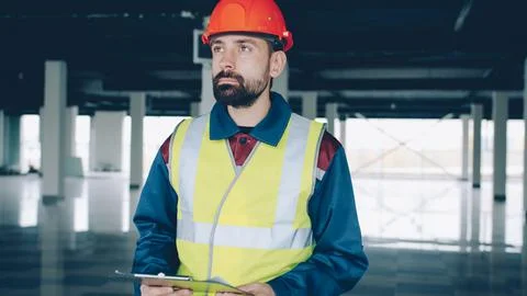 Construction inspector checking papers and studying industrial building inside Stock Photos
