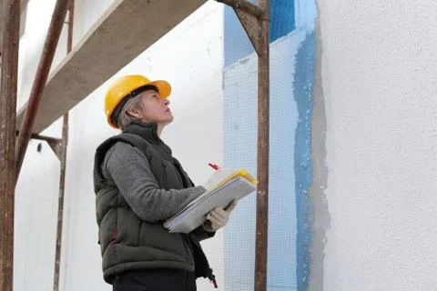 Construction inspector examine styrofoam insulation of house facade Photos