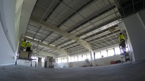 Construction, installing ceiling tiles to the grid in large area Stock Footage 89701576