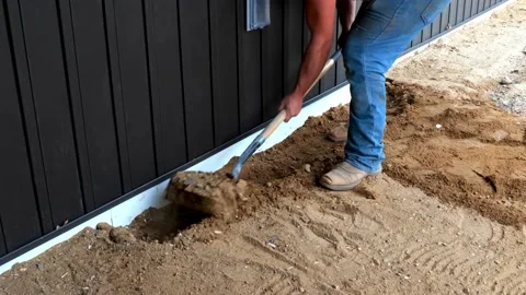 Construction laborer uses spade to move dirt near a house foundation. Stock Footage 153861973