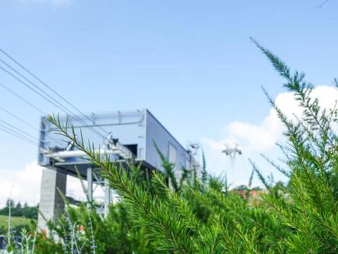 Construction of a large cable car against the blue sky behind the branches of Stock Photos