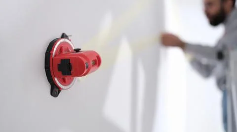 Construction laser level is fixed on wall. Builder makes repairs in apartment Stock Photos