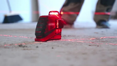 Construction laser level installed on the floor on building site, red laser rays Video stock 133772905
