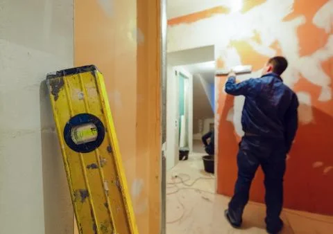 Construction level on the foreground and worker is working with palette-knife Stock Photos