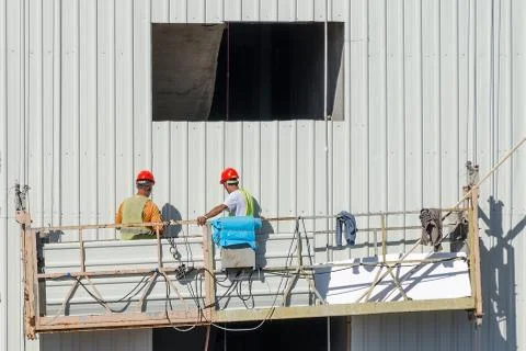 Construction lifting platform elevate builders at wall. Stock Photos