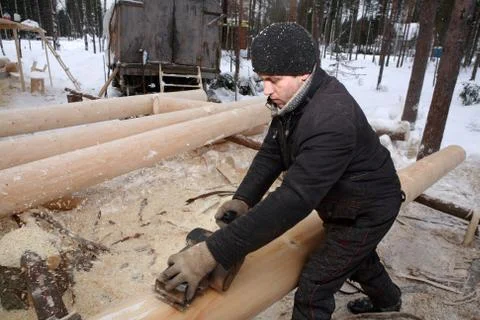 Construction of a log cabin, planing of a log by an electric jack-plane. Stock Photos