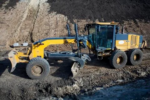 The construction machine Motor Grader level the ground with the construction of Stock Photos