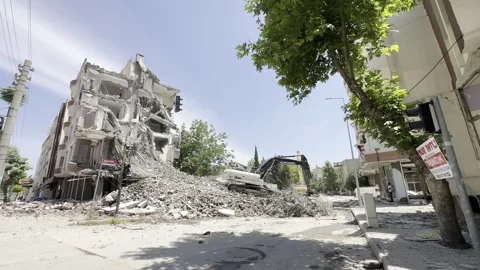 A construction machine working in front of a ruined building. An excavator. Stock Footage 243317598