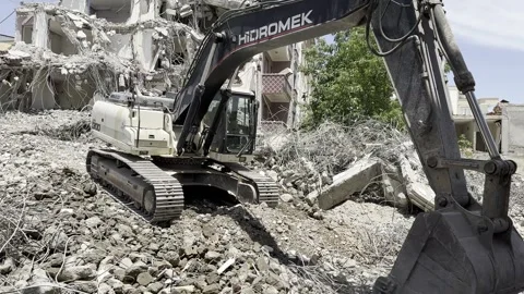 A construction machine working in front of a ruined building. An excavator. Stock Footage 243317690