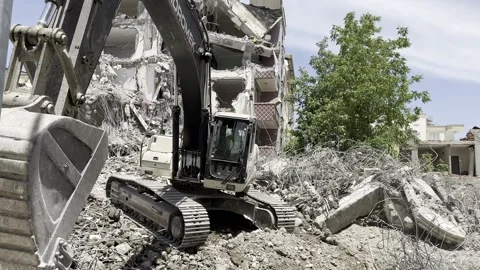 A construction machine working in front of a ruined building. An excavator. Stock Footage 243317778