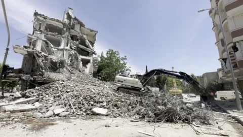 A construction machine working in front of a ruined building. An excavator. Stock Footage 243317785