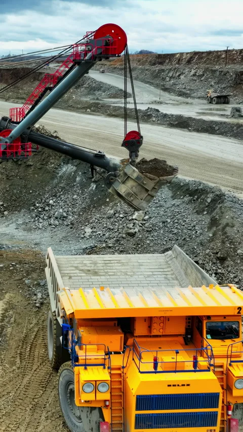 Construction machinery expertly navigates quarry terrain to load materials into Stock Footage 321972883