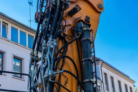 Construction machinery extends its arm near urban buildings Stock Photos
