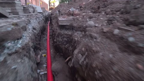 Construction made of red metal-plastic tape lies in pit dug on city street. Stock Footage 183007693