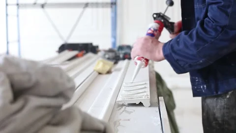 Construction, male builder glues ceiling cornice with liquid nails, white Stock Footage 303406575