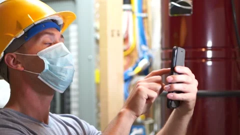 Construction man wearing mask using phone at work Stockbeeldmateriaal 137110404