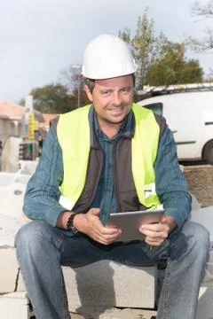 Construction man worker looking in tablet computer pad while sitting outdoor Stock Photos