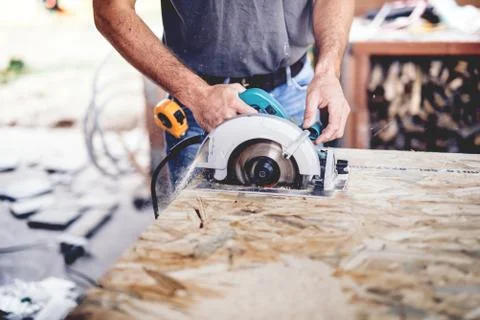 Construction man working with a chop saw in wood workshop. Cutting wood Stock Photos