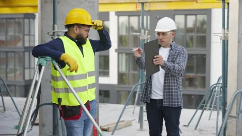 Construction manager and surveyor discussing project on site Stock Footage 343450124