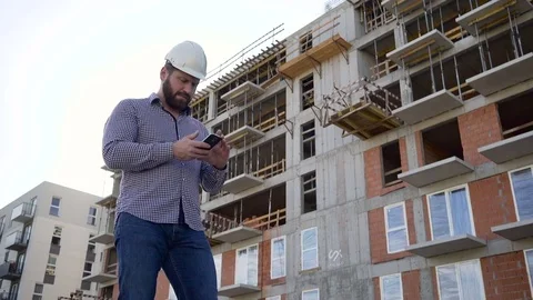 Construction manager browsing smartphone at building place. 库存影片 70804803