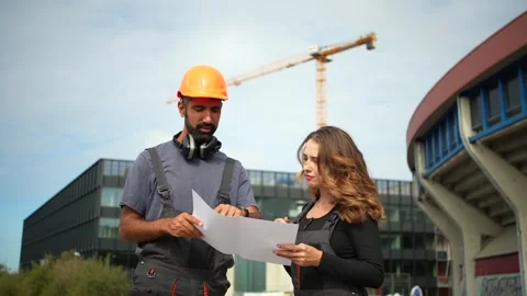 Construction manager discussing project blueprint with female engineer on site Stock Footage 348274608