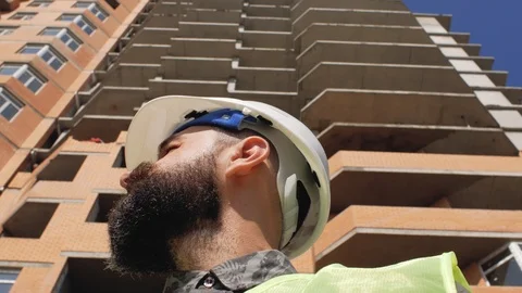 Construction manager in a helmet on the background of a high-rise building.4k Видео 105676947