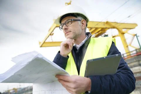 Construction manager on site reading blueprint Stock Photos
