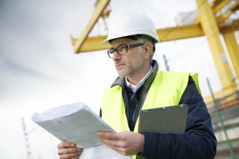 Construction manager on site reading blueprint Stock Photos